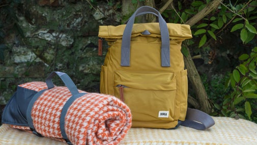 A yellow back pack and orange picnic blanket
